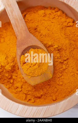 Immagine ravvicinata di curcuma o curry in polvere in cucchiaio di legno Foto Stock