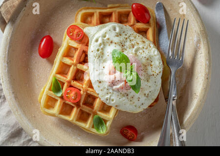 Waffles fatti in casa con uova fritte e pomodorini Foto Stock