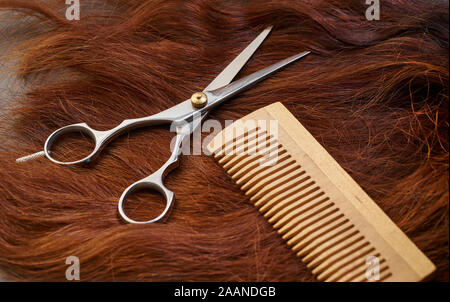 Parrucchiere forbici e pettine su uno sfondo di capelli Foto Stock