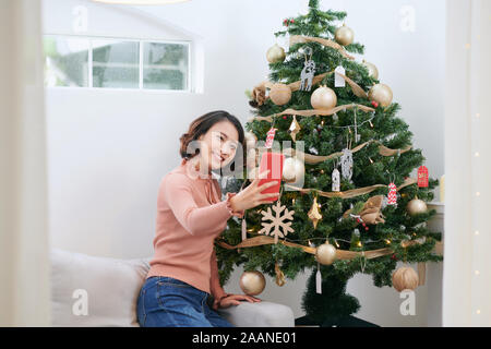 Concetto di natale - giovane donna prendendo selfie foto vicino albero di Natale decorato Foto Stock