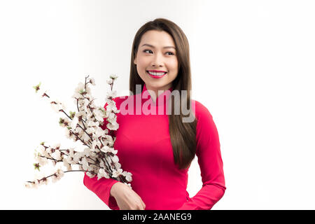 Belle Donne vietnamita in abito tradizionale, sorridente e trattenere i rami di pesco in fiore Foto Stock