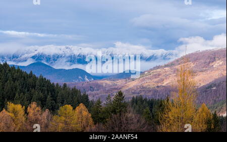 Paesaggio Transilvania Novembre 2019 con Piatra Craiului montagne coperte di neve, foggye vista sul villaggio di crusca Foto Stock