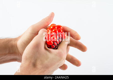 Maschio di schiacciamento mani palla su sfondo semplice Foto Stock