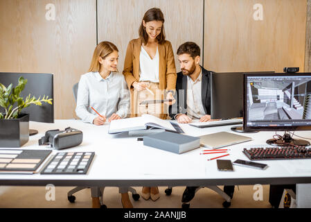Piccolo gruppo di creativi di impiegati che lavorano insieme su alcuni progetti architettonici dell'ufficio moderno. Concetto di un patrimonio architettonico di business e il lavoro creativo Foto Stock