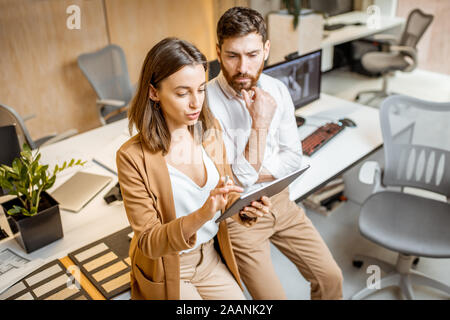 I colleghi aventi qualche lavoro creativo utilizzando tavoletta digitale e matita in ufficio moderno studio. Concetto di progettazione digitale su un tablet Foto Stock