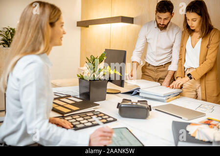 I giovani lavoratori vestito casualmente facendo qualche lavoro creativo al tavolo di grandi dimensioni con i computer in ufficio. Concetto di un patrimonio architettonico di business e il lavoro creativo Foto Stock