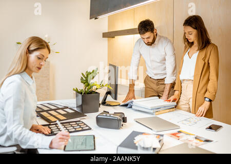 I giovani lavoratori vestito casualmente facendo qualche lavoro creativo al tavolo di grandi dimensioni con i computer in ufficio. Concetto di un patrimonio architettonico di business e il lavoro creativo Foto Stock