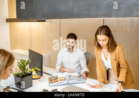 I giovani lavoratori vestito casualmente facendo qualche lavoro creativo al tavolo di grandi dimensioni con i computer in ufficio. Concetto di un patrimonio architettonico di business e il lavoro creativo Foto Stock