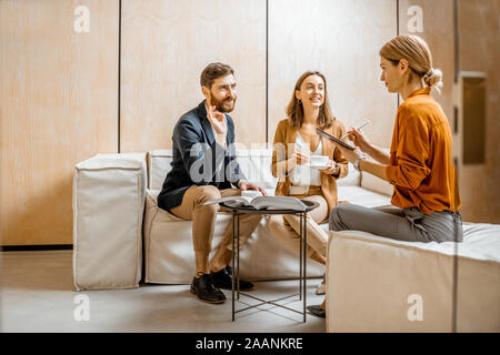 Coppia giovane parlando con la donna come sales manager, consulente finanziario o psicoterapeuta, seduto su un confortevole lettino in ufficio Foto Stock