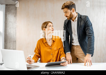 Imprenditore avente alcune conversazioni informali con un collega di lavoro o la donna boss in ufficio Foto Stock