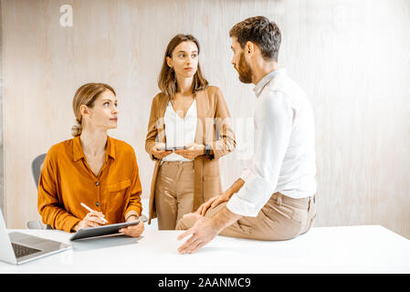 Dipendenti in sede avente alcune conversazioni informali presso il luogo di lavoro in ufficio Foto Stock