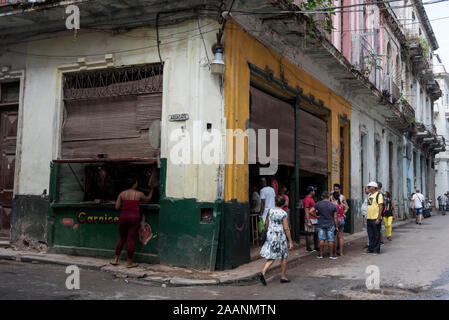 Un residente alla vetrina della macelleria con una piccola coda ad un frutteto dietro l'angolo nella città Vecchia dell'Avana a Cuba. Foto Stock