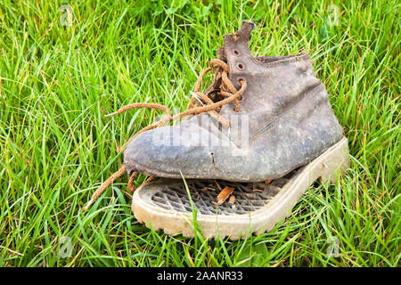 Vecchio boot rotto abbandonato in un tappeto d'erba Foto Stock