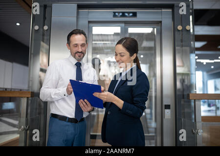 Paio di imprenditori la lettura di alcune relazioni in attesa di ascensore Foto Stock