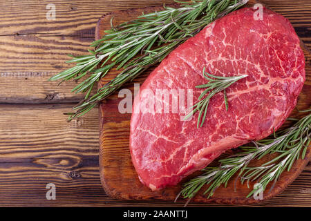 Crudo fresco bistecche servite con i rametti di rosmarino rustico di legno Foto Stock