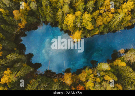 In autunno la foresta e lago blu vista aerea acqua turchese riflesso colorato incorniciato da alberi di pino paesaggio deserto viaggi scenario in Finlandia Foto Stock