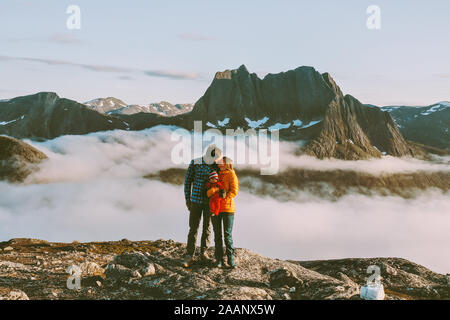 Famiglia giovane baciare sulla cima della montagna che viaggiano con baby escursionismo insieme in Norvegia un uomo e una donna su uno stile di vita sano vacanze attive outdoor sentimenti Foto Stock