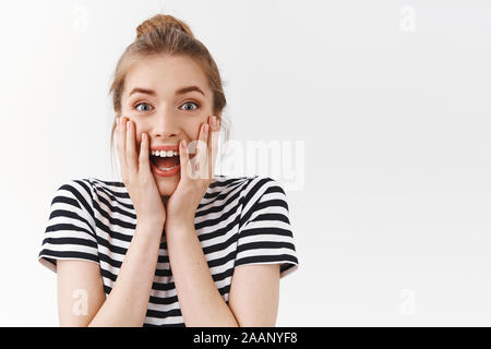 Close-up eccitato, divertito bella donna con bun disordinato, striped t-shirt, urlo dal divertimento e stupore reagiscono al meraviglioso e fantastico news Foto Stock