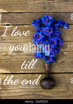 Bouquet di molto luminoso e colorato delphinium blu fiori in un piccolo vaso di creta sul legno rustico squallido sfondo usurati, piatto di laici che, vista dall'alto, clo Foto Stock