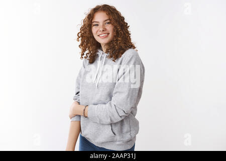 Carino insicuro redhead giovane ragazza adolescente con lentiggini capelli ricci indossando felpa con cappuccio grigio sorridente toccare il braccio insicuro arrossendo grinning cordiale conversazione Foto Stock