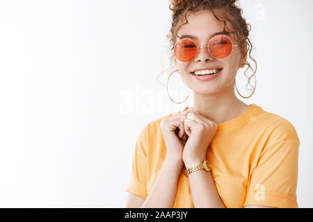 Elegante Attraente giovane ragazza adolescente indossando occhiali da sole rotonda t-shirt sorridente desiderosi guarda il nuovo filmato coda permanente concerto preferito entusiasta Foto Stock