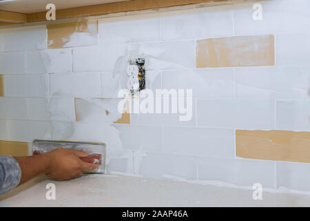 La piastrella di lavoro intonacando applicazione boiacca per il comune di piastrelle per miglioramenti di casa ad una cucina Foto Stock