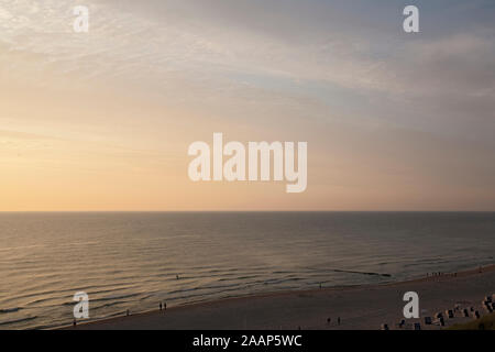 Untergehende Sonne zwischen Meer und Wolken am Strand bei Wenningstedt auf Sylt Foto Stock