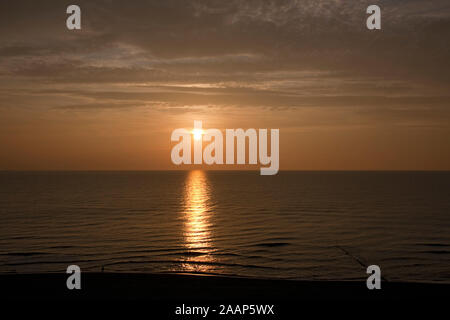 Untergehende Sonne zwischen Meer und Wolken am Strand bei Wenningstedt auf Sylt Foto Stock