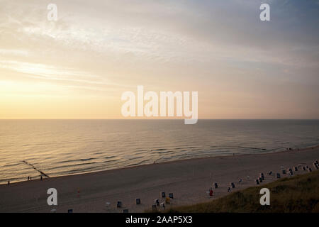 Untergehende Sonne zwischen Meer und Wolken am Strand bei Wenningstedt auf Sylt Foto Stock