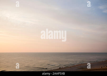 Untergehende Sonne zwischen Meer und Wolken am Strand bei Wenningstedt auf Sylt Foto Stock