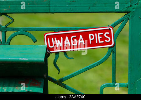 "Uwaga pies' firmare con il significato di "attenzione del cane' in polacco. Il segno è su un verde recinzione metallica gate. Foto Stock