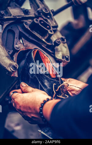 Le mani di un calzolaio esperto utilizzando una speciale macchina utensile per la realizzazione di calzature. Pattino del processo di produzione in fabbrica. Messa a fuoco selettiva Foto Stock