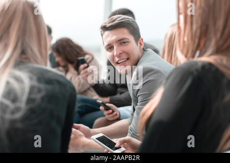 Sorridente ragazzo seduto in un cerchio per un incontro di gruppo Foto Stock