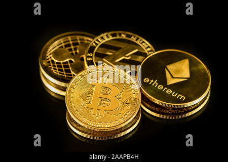 Colore oro monete fisiche di common crypto valute in piena luce sul nero superficie a specchio Foto Stock