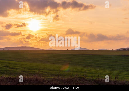 Tramonto sul campo verde con giallo Cielo e nubi Foto Stock