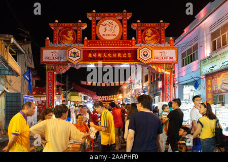 La gente a piedi attraverso sotto l'arco cinese durante il weekend night-mercato in Malacca, Malesia Foto Stock