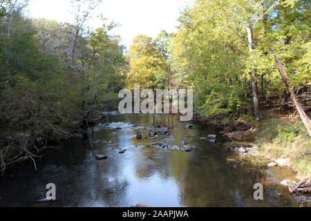 Il fiume Eno scorre su rocce e massi attraverso una foresta in Eno River State Park, North Carolina, Stati Uniti d'America, in una giornata di sole Foto Stock