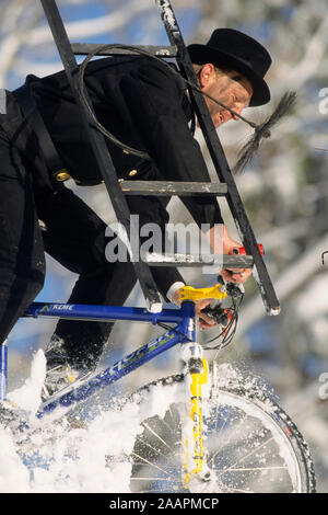 Schornsteinfeger auf dem Mountainbike im Schnee Foto Stock