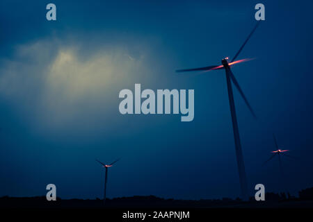 Le turbine eoliche su un drammatico blu scuro nuvole nel cielo. Tempesta davanti è venuta. Accensione della spia rossa del mulino a vento Foto Stock