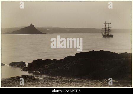 Il Brigantino 'Astrid' all ancora a monte's Bay off Penzance, Cornwall, Regno Unito: St. Michael's Mount al di là. Aspetto antico: seppia-tonico e con bordi grezzi Foto Stock