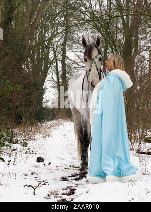 Una magica cercando girl e cavallo in un paesaggio innevato. Foto Stock