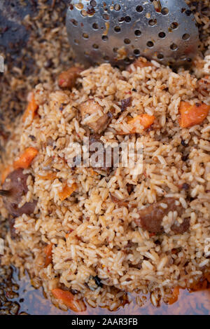 Fragrante delizioso pilaf con aglio e pepe di grandi dimensioni. Street festosa cibi preparati al momento. Deliziosi piatti di riso. Bella pilaf allentato. Carne e riso. Gar Foto Stock