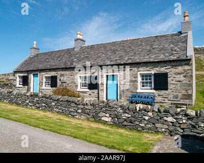 Fila di smart vecchio cottage in pietra con persiane alle finestre e porte blu utilizzato da RSPB sull'Isola di Oronsay, Colonsay, Scotland, Regno Unito Foto Stock