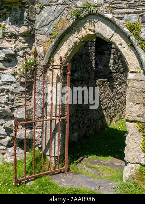 Antica pietra arco ogivale porta con open vecchio cancello arrugginito, Oronsay Priory, Isola di Oronsay, Colonsay, Scotland, Regno Unito Foto Stock