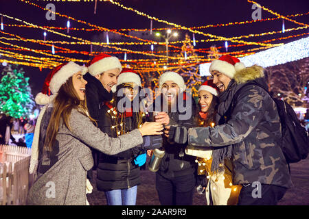 Un gruppo di amici bevendo un tè caldo in una fiera di Natale Foto Stock