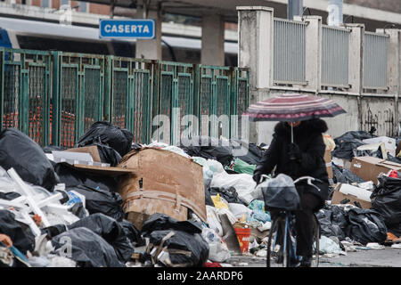 Caserta, Italia, 21 Febbraio 2008: una donna su una bicicletta passa da accumulo di rifiuti in una strada a Caserta, Italia, a nord di Napoli durante la Napoli gestione dei rifiuti crisi nel 2008. Foto Stock