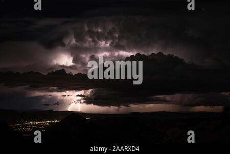 Acquazzone porta inondazioni improvvise e lampi di deserto dello Utah vicino a Moab. Lontani i fulmini illuminano la notte e massiccia thunderclouds uovere Foto Stock