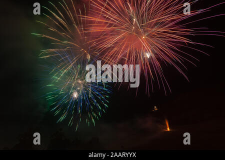 Colorato esplosioni di fuochi d'artificio su alberi silhouette Foto Stock