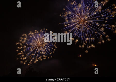 Oro e blu fuochi d'artificio che illumina il cielo sopra una chiesa illuminata Foto Stock