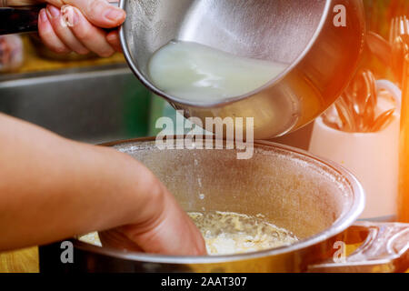 Versare acqua in ciotola con la farina a fontana sul tavolo in una panetteria Foto Stock